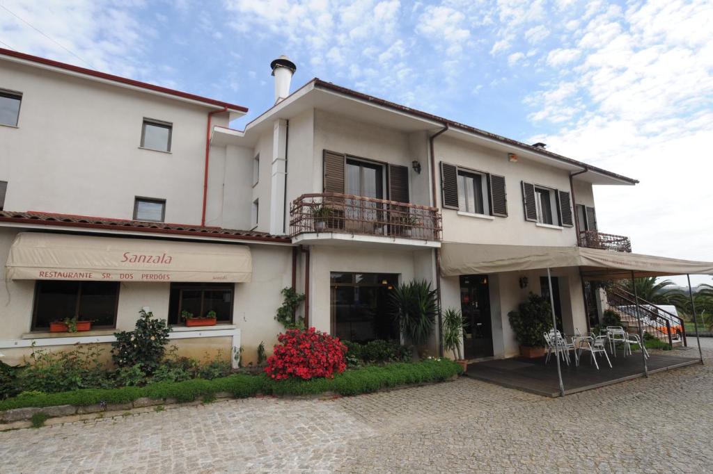 um grande edifício branco com um restaurante em frente em Senhor dos Perdoes Alojamento Local em Ribeirão