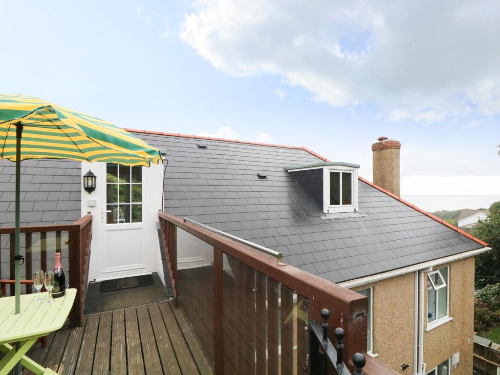 a balcony with a wooden deck with an umbrella at The Watch in Porthcurno