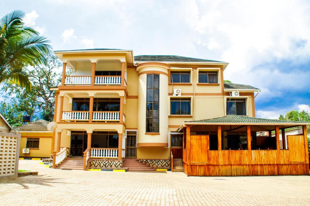 een geel huis met een hek ervoor bij Alfa Hotel Munyonyo in Kampala