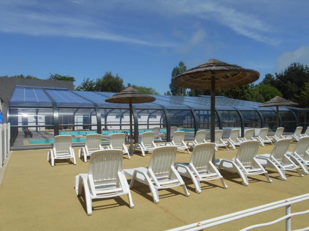 una fila de sillas y sombrillas blancas en un patio en Bontempo Village, en Piriac-sur-Mer