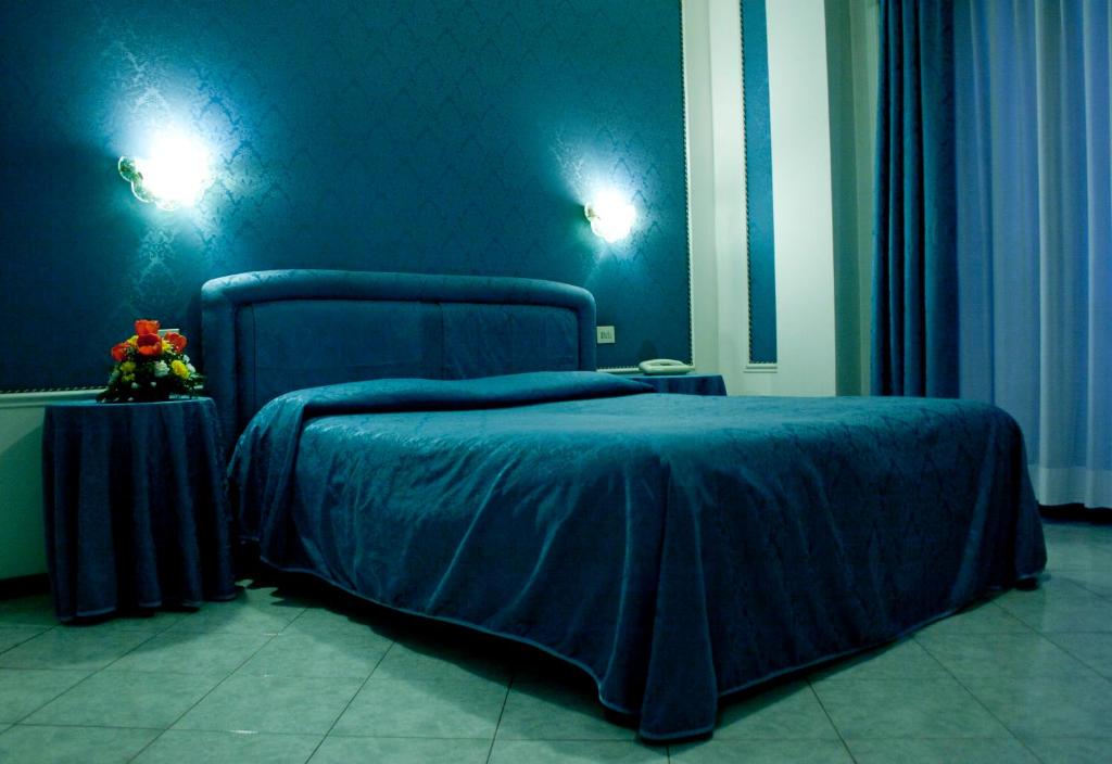 - une chambre bleue avec un lit et une table fleurie dans l'établissement Hotel Michelangelo, à Rezzato