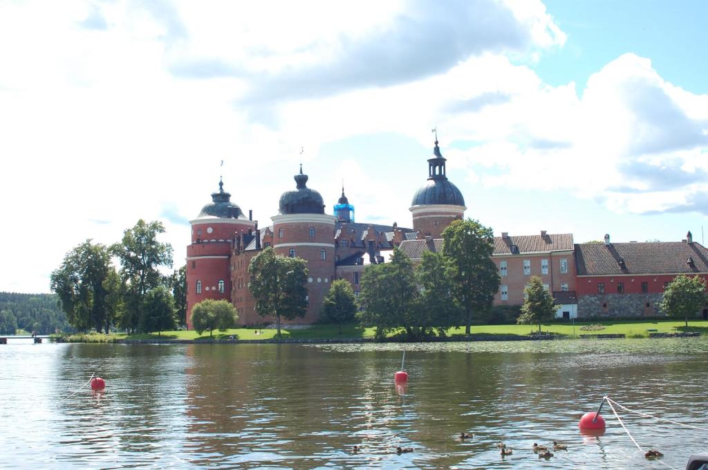 un castello sull'acqua di fronte a un edificio di Röda Magasinet a Mariefred