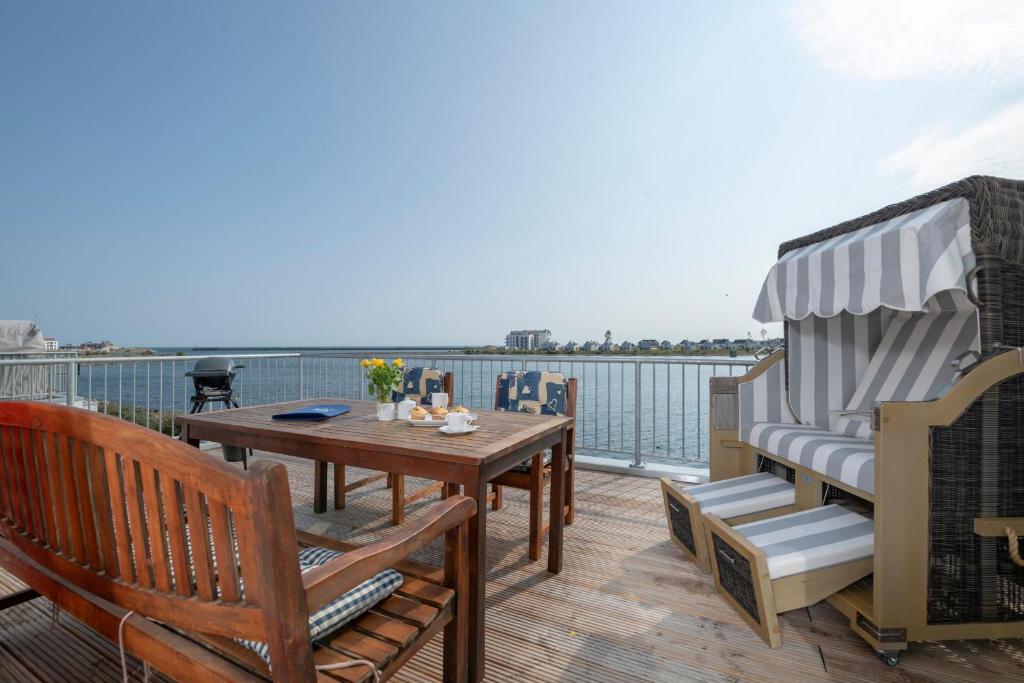 a balcony with a table and chairs and the water at Strandelfe in Olpenitz