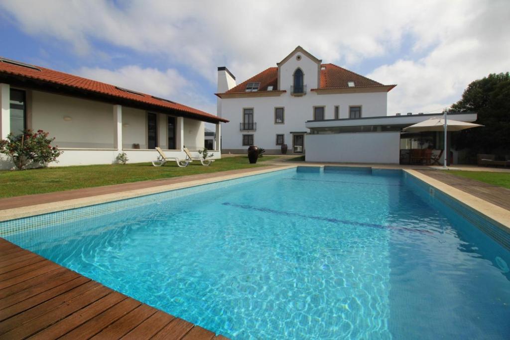 a large blue swimming pool in front of a house at Quinta da Aldeia de Avanca in Avanca