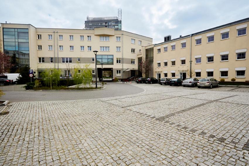 un aparcamiento con coches estacionados frente a los edificios en Centrum Okopowa 55, en Varsovia