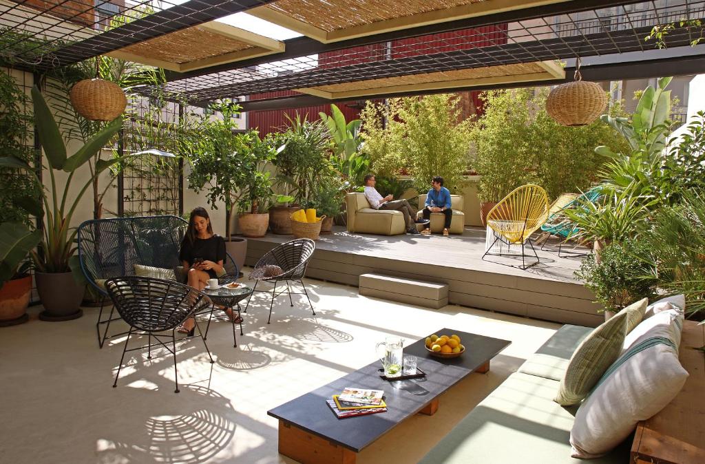 a patio with people sitting on chairs and a table at Chic & Basic Lemon Boutique Hotel in Barcelona