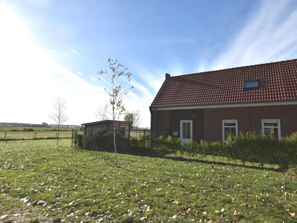 a house with a field next to a building at house in a quiet park with sauna in Breskens
