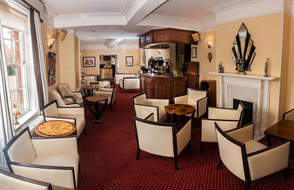 um restaurante com cadeiras e mesas e uma lareira em Beechwood Hotel em North Walsham