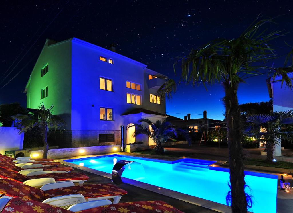 una casa con piscina por la noche en Apartments Bracic Spa, en Sukošan