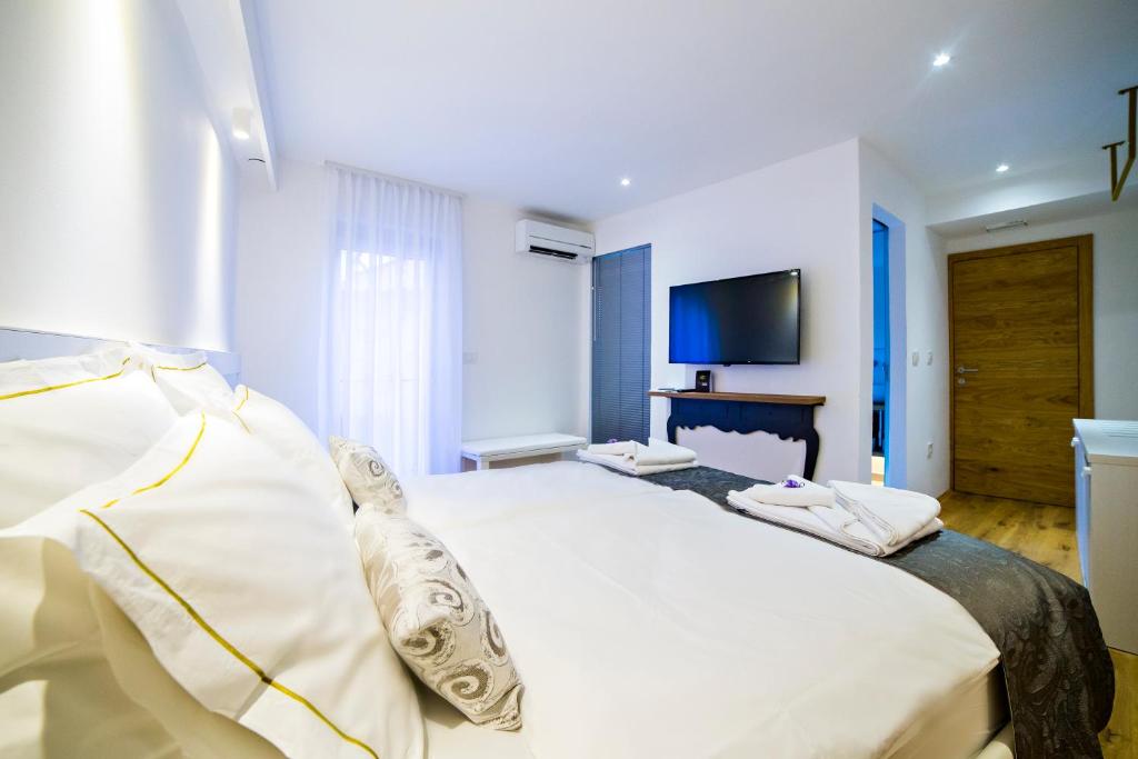 a bedroom with a large white bed and a flat screen tv at MEMENTO B&B Piran in Piran