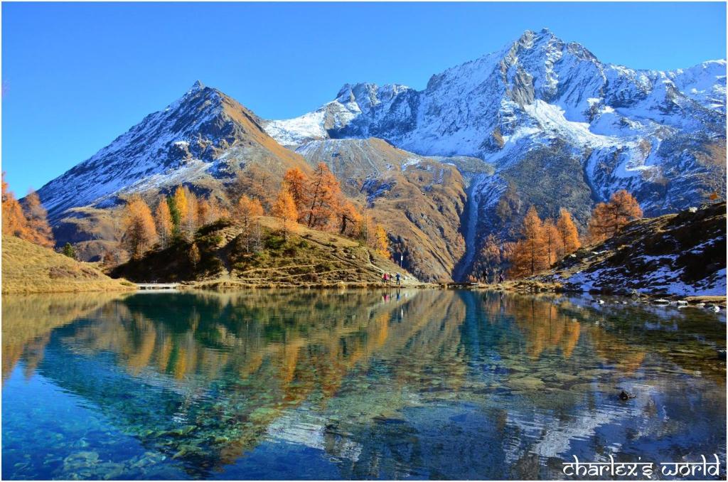 a mountain reflecting in a lake in the mountains at Hôtel Pension du Lac Bleu in La Gouille