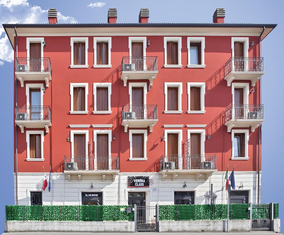 czerwony budynek z balkonami na ulicy w obiekcie Verona Class ApartHotel "Residenze del Cuore" w Weronie
