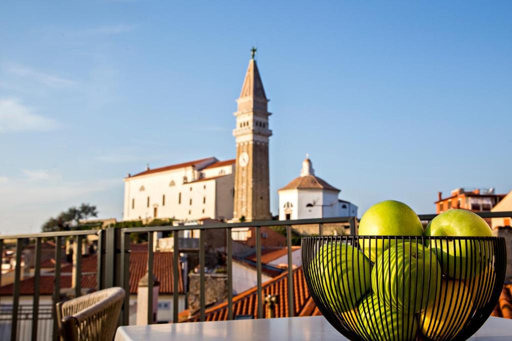 a bowl of fruit on a table with a clock tower at MEMENTO B&B Piran in Piran
