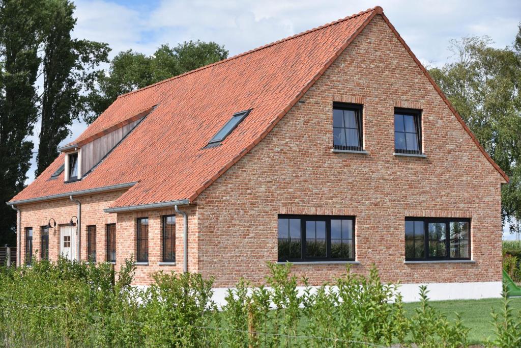 una casa de ladrillo con techo rojo en Fermette de bobonne en Poperinge