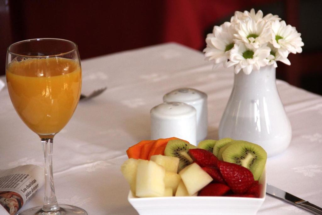 a plate of fruit next to a glass of orange juice at Hotel Principe Paz in Santa Cruz de Tenerife