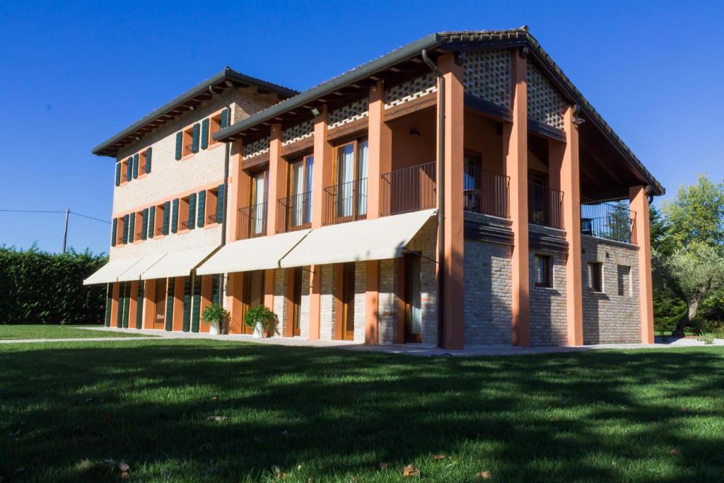 a large brick building with a grass field in front at Crystal Luxury House in Fiume Veneto