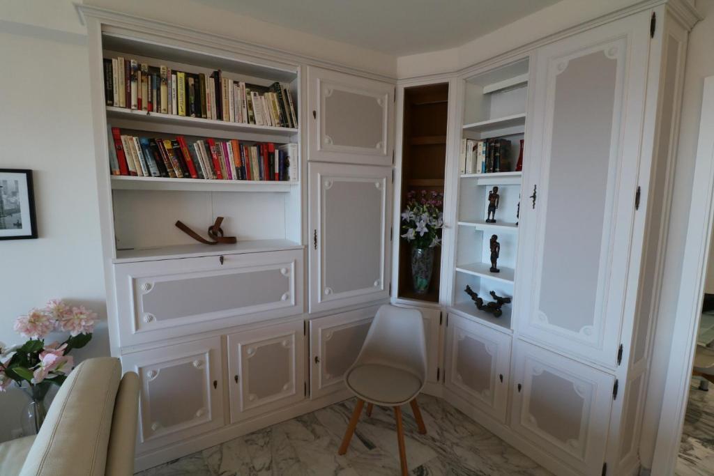 a room with white book shelves and a chair at 2, 3 and 4 bedroom sea view Forville Apartments 5 mins from the Palais in Cannes