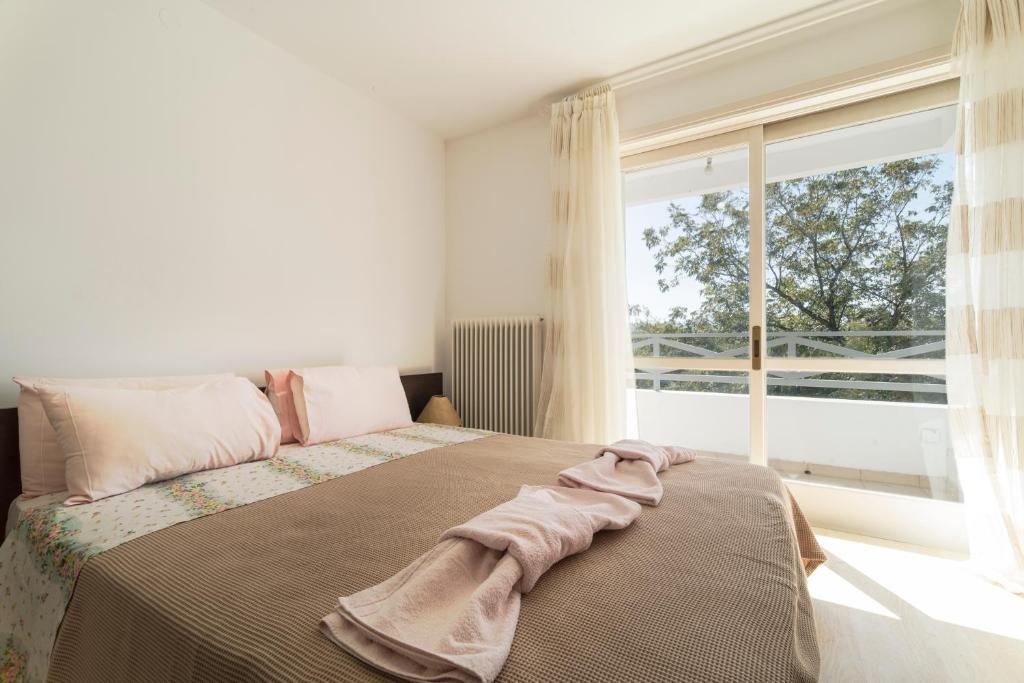 Un dormitorio con una cama con una ventana grande. en Holiday home next to orange tree orchard, en Vrachati