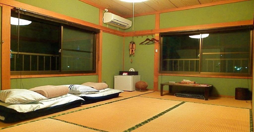 uma sala de estar com um sofá e duas janelas em Private Twin Room - Aoshima Guesthouse Hooju - Vacation STAY 6392 em Miyazaki