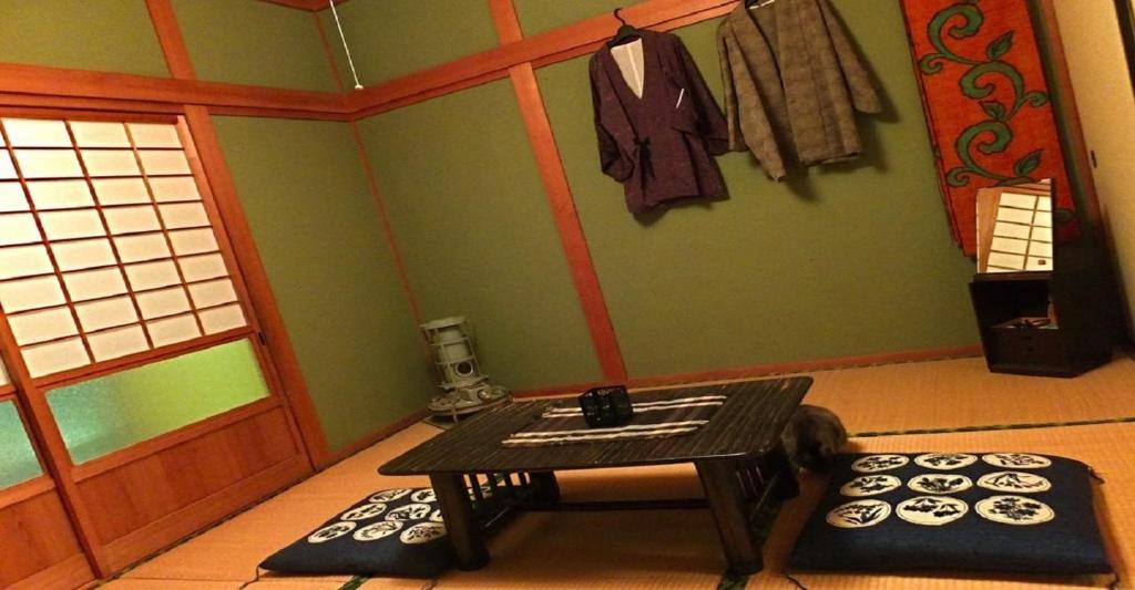 uma sala de estar com uma mesa e uma sala com tapetes em 8Bed Dormitory Room - Aoshima Guesthouse Hooju - Vacation STAY 6198 em Miyazaki