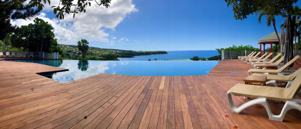 a swimming pool with chairs on a wooden deck at Le Rayon Vert in Deshaies