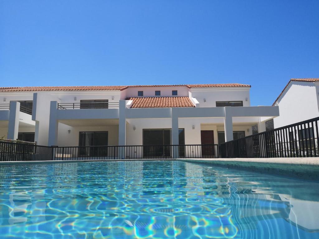 a villa with a swimming pool in front of a house at Pinares de Higuerillas in Maitencillo