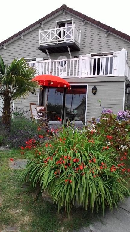 une maison avec une table, un parasol et des fleurs dans l'établissement Appartement rdc les flots, à Varengeville-sur-Mer