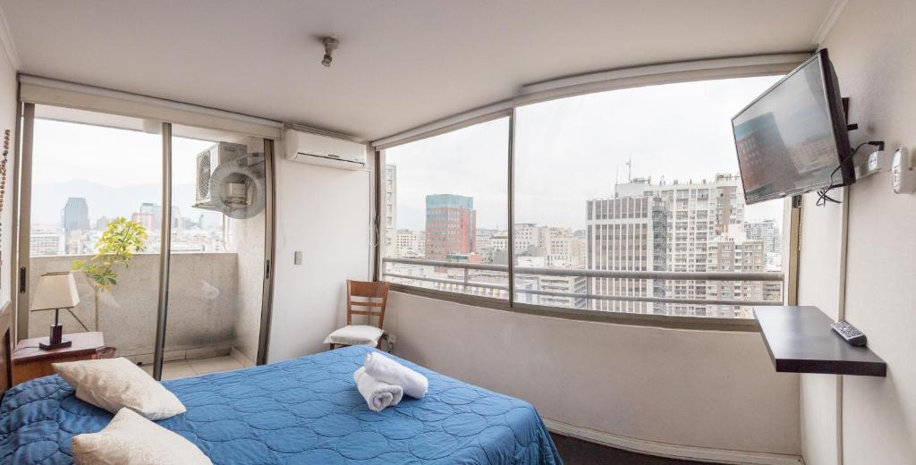 a bedroom with a blue bed and a large window at Zenteno Apartments in Santiago