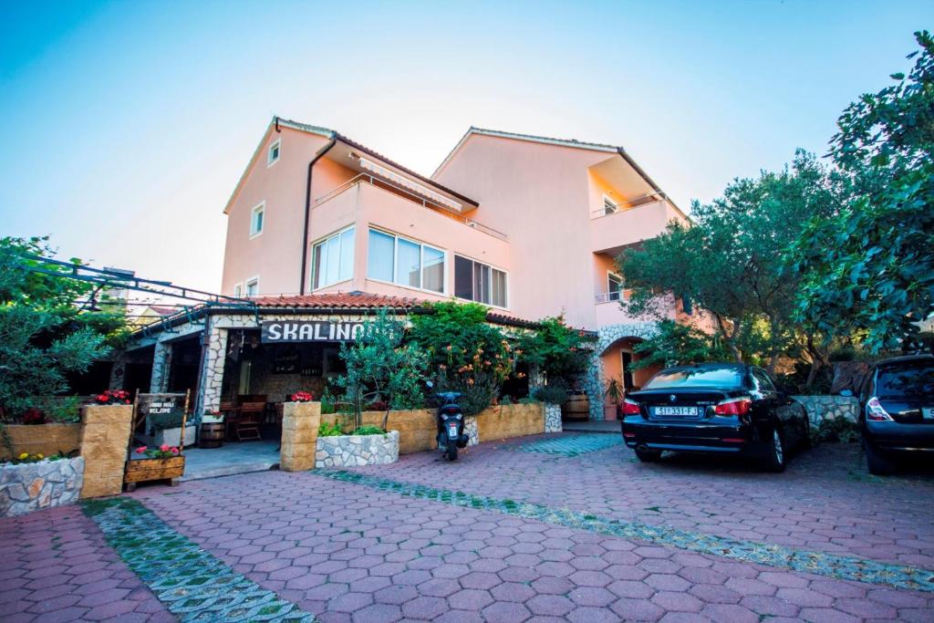 un bâtiment avec une voiture garée devant lui dans l'établissement Apartments and Rooms Skalinada, à Murter