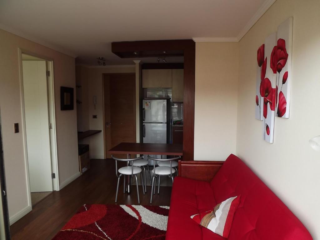 uma sala de estar com um sofá vermelho e uma cozinha em Departamento En Viña Del Mar em Viña del Mar