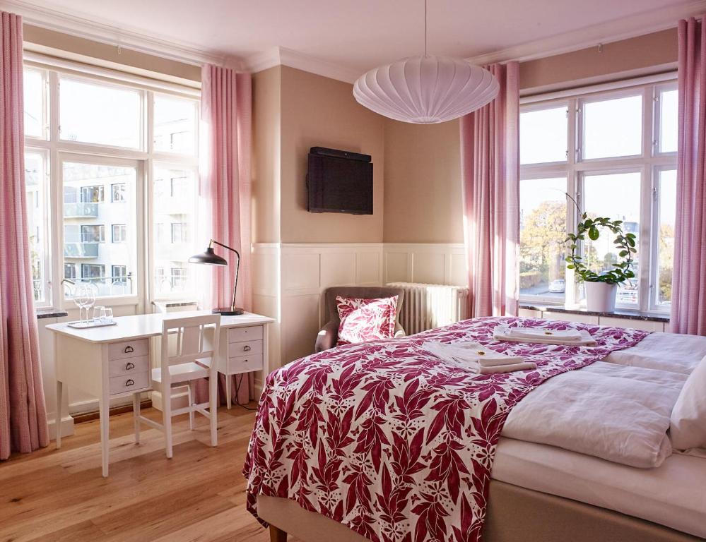 a bedroom with a bed and a desk and windows at MillasVilla in Lund