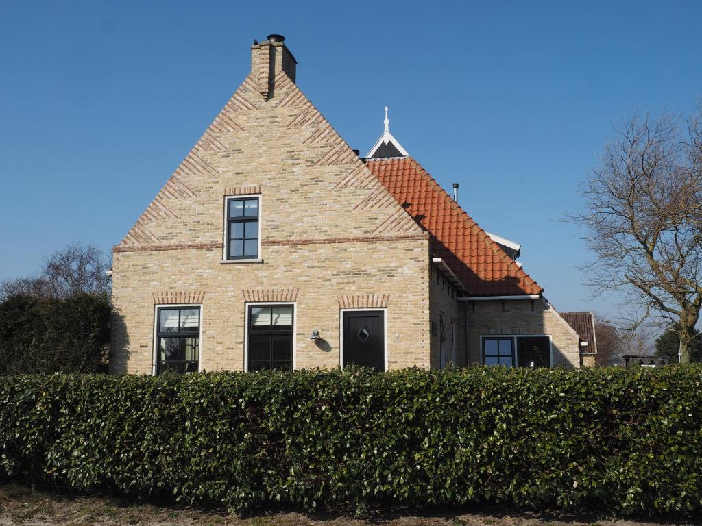 Una gran casa de ladrillo con una cruz encima. en De Vergulde Kikker, en Baaiduinen