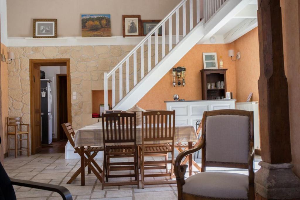 une salle à manger avec une table, des chaises et un escalier dans l'établissement Les Ruchers d'Emile, à Landécourt