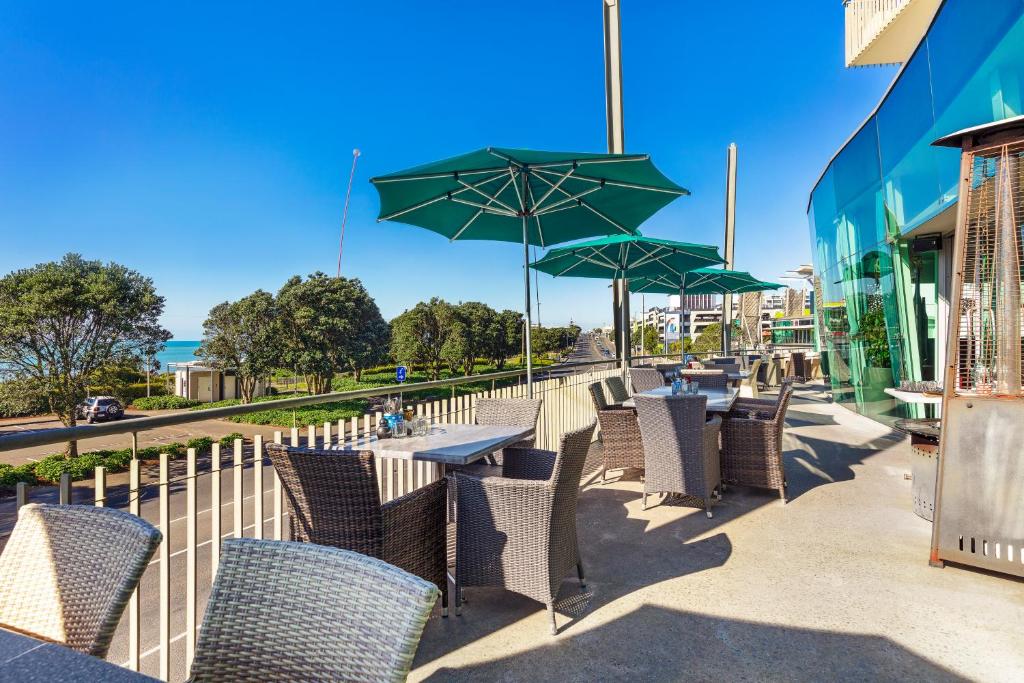 a row of tables and chairs with green umbrellas at Millennium Hotel New Plymouth, Waterfront in New Plymouth