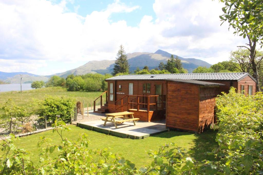 a small cabin in a field with mountains in the background at Mountain View in Taynuilt