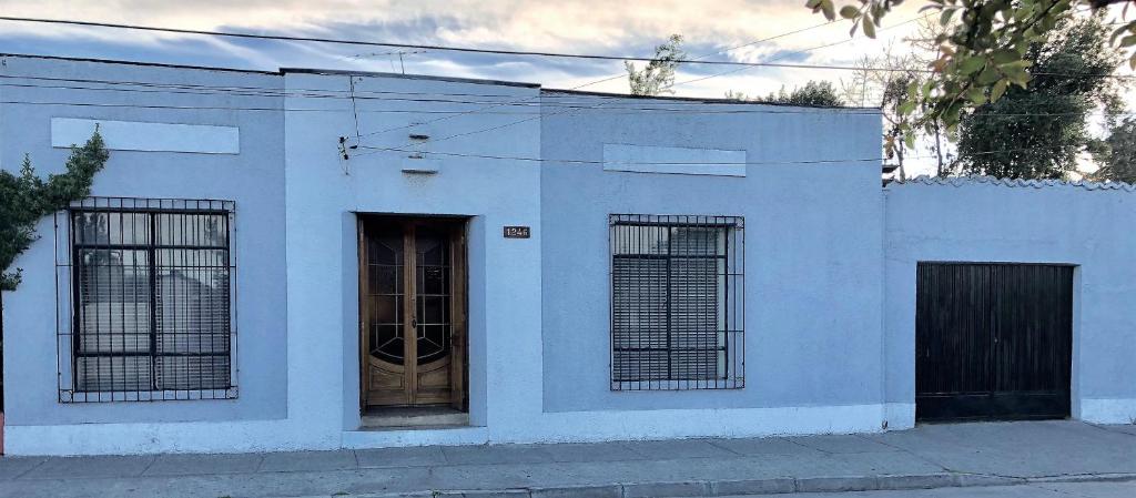 un edificio blanco con tres ventanas y una puerta en Casa Familiar Las Yerbas, en Molina
