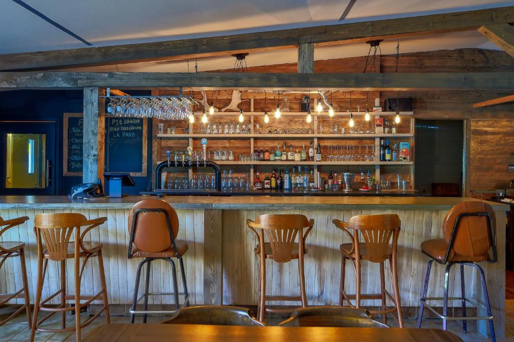 un bar con taburetes de madera en un restaurante en Auberge de Jeunesse Le Camp De Base, en L'Anse-Saint-Jean