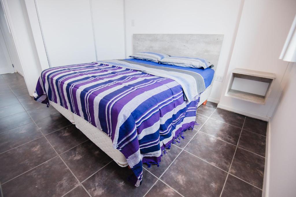 Un dormitorio con una cama con una manta a rayas. en Apart FJL en Río Cuarto