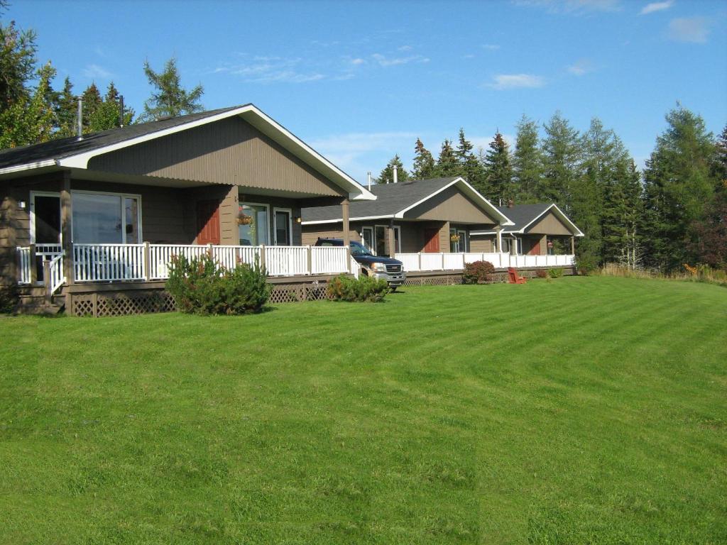 una casa con un gran césped delante de ella en McIntyre's Cottages, en Baddeck Inlet