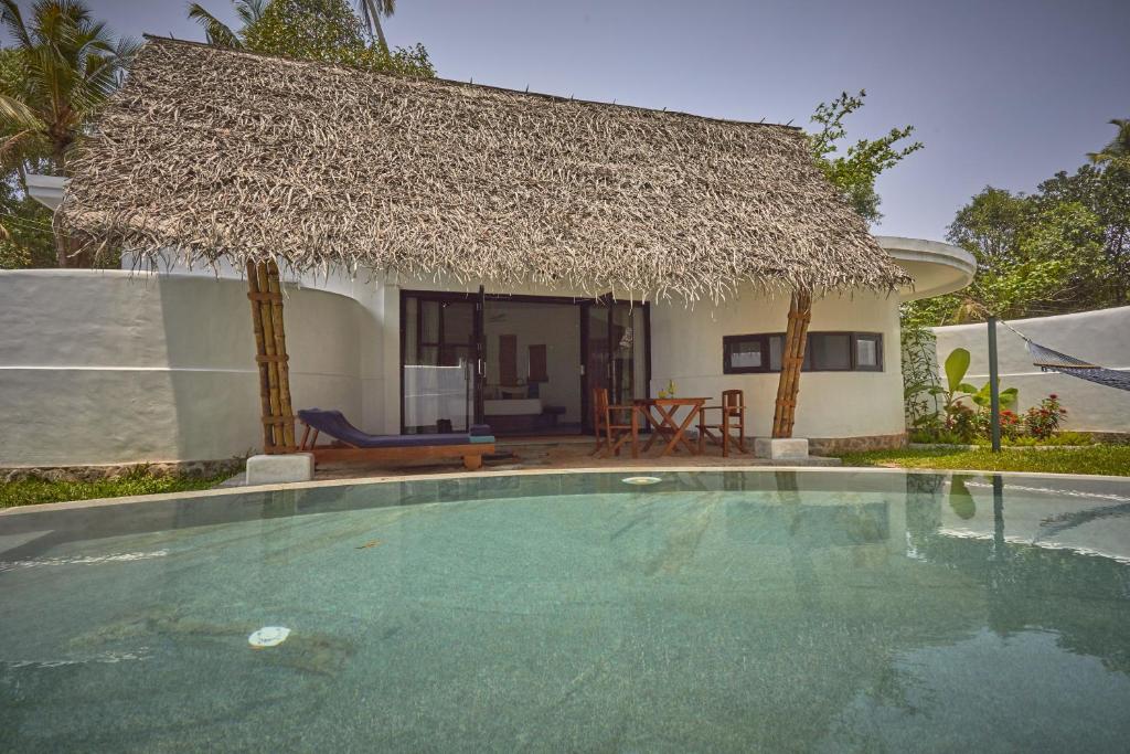 a villa with a swimming pool in front of a house at Xandari Pearl Beach Resort in Mararikulam