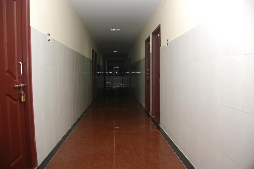 einen leeren Flur mit weißen Wänden und roten Türen in der Unterkunft VENKKATRAMANAA RESIDENCY in Kumbakonam