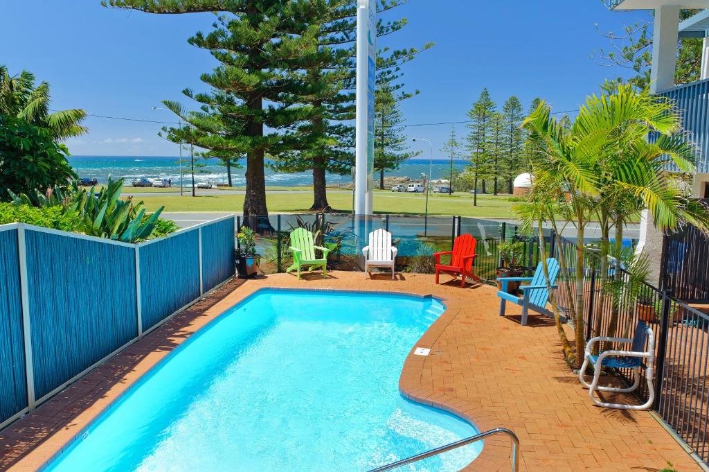 a patio area with a pool, chairs, and a pool table at Beach House Holiday Apartments in Port Macquarie