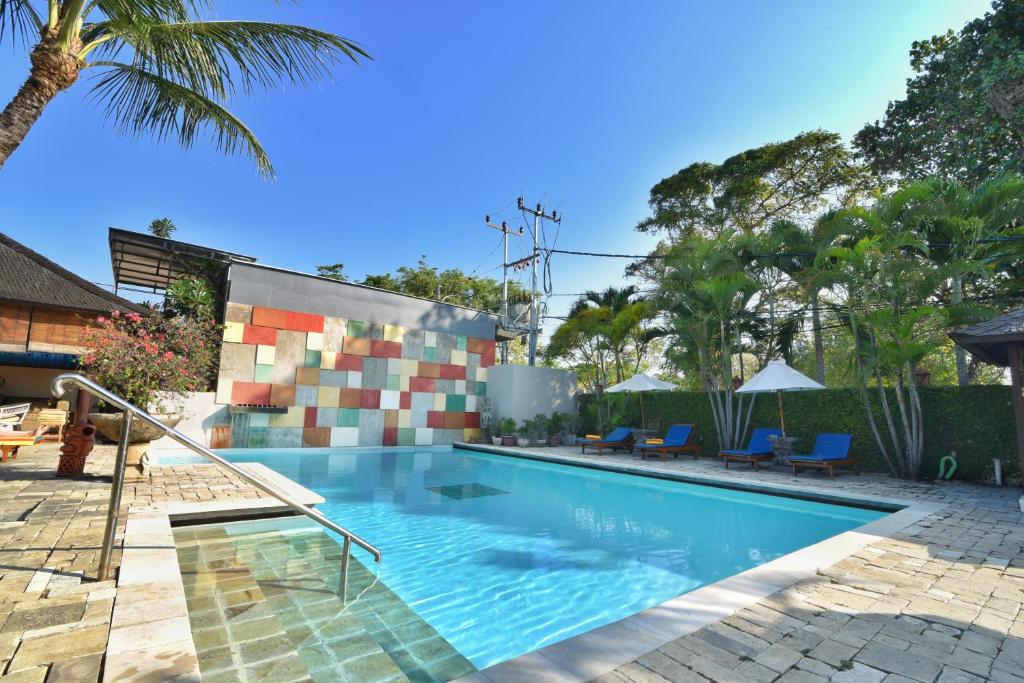 een zwembad in een resort met een palmboom bij Palm Garden Hotel in Sanur