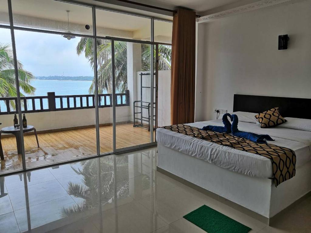 a bedroom with a bed and a view of the ocean at Cool Beach Hotel in Hikkaduwa