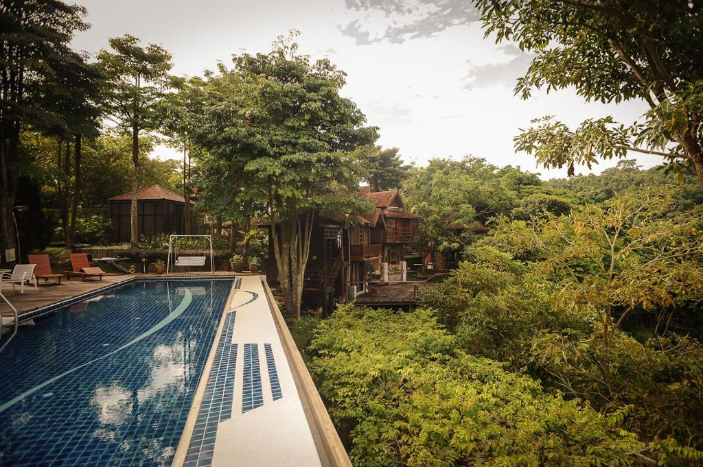 a swimming pool in front of a house with trees at MaliHom Private Estate in Balik Pulau