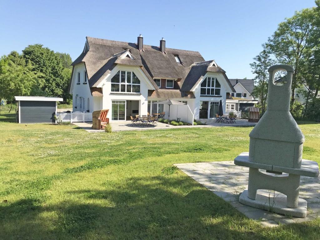 uma casa grande com uma estátua em frente em Reetperle Lobbe - Ferienhaus mit Sauna (F 650) em Lobbe