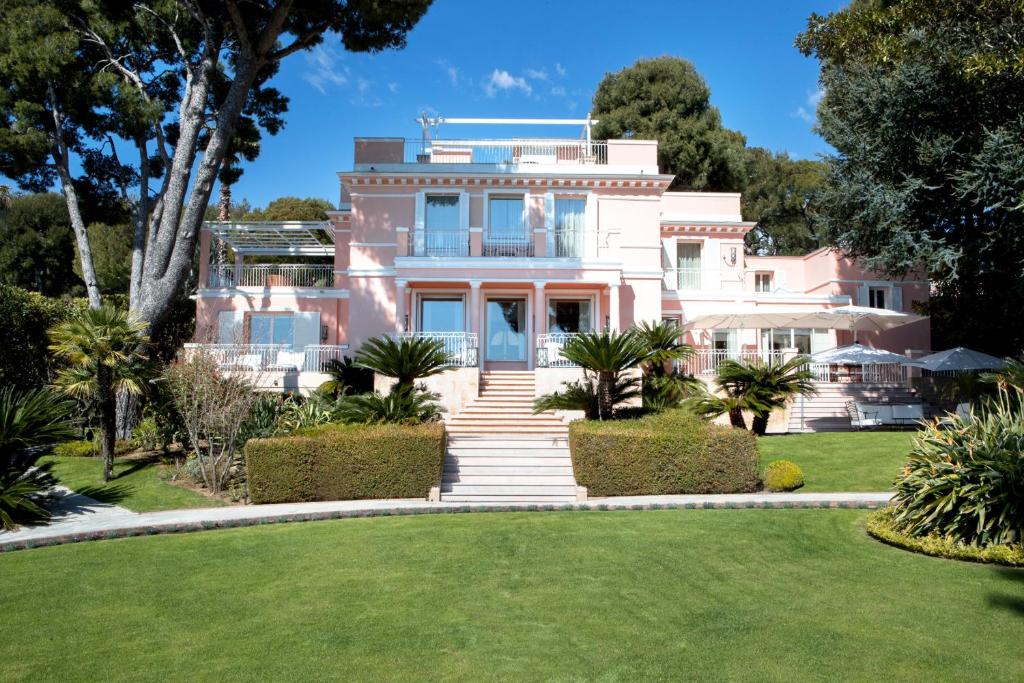 a pink house with a lawn in front of it at Grand-Hôtel du Cap-Ferrat, A Four Seasons Hotel in Saint-Jean-Cap-Ferrat