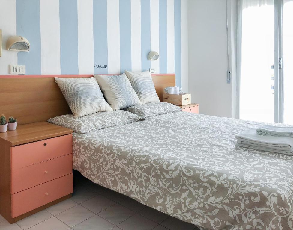 een slaapkamer met een bed met een gestreepte muur bij Alba B&B in Cattolica