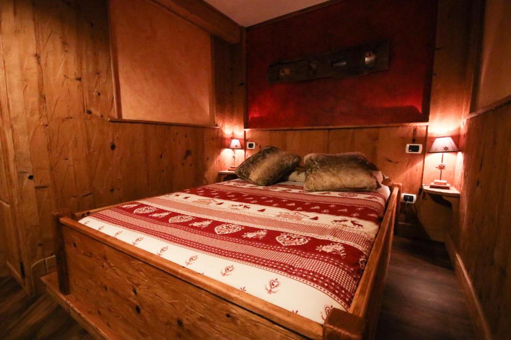 Cama en habitación de madera con 2 almohadas en Maison D'Antan Alloggio ad uso turistico VDA CHARVENSOD n 0022, en Aosta