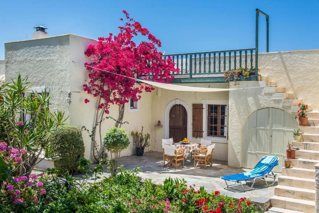 dom ze stołem, krzesłami i kwiatami w obiekcie Bougainvillea House in Crete w mieście Sitia